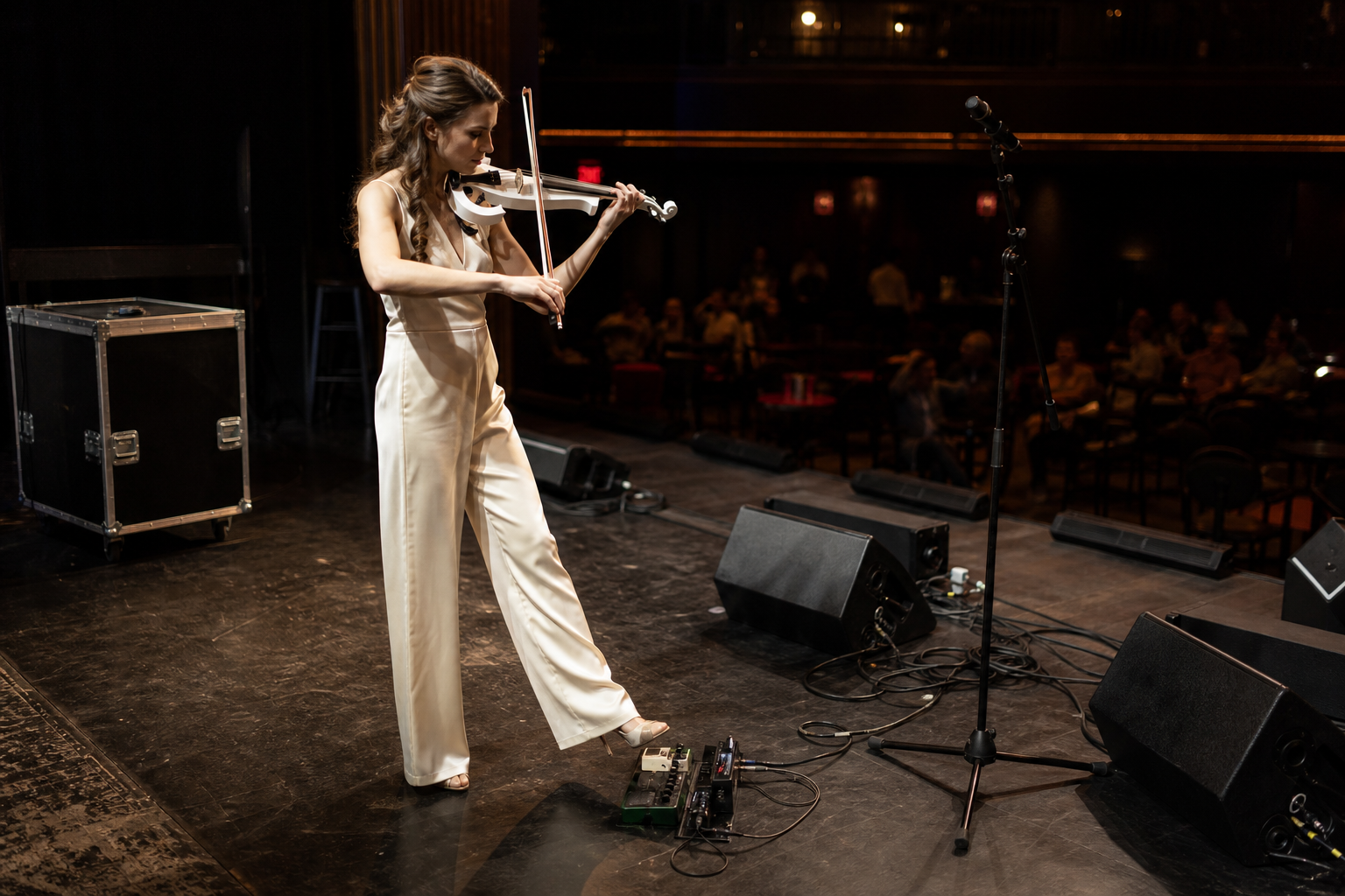 Electric violin performer on stage during soundcheck with one foot near a clean boost pedal and wedge monitors ready