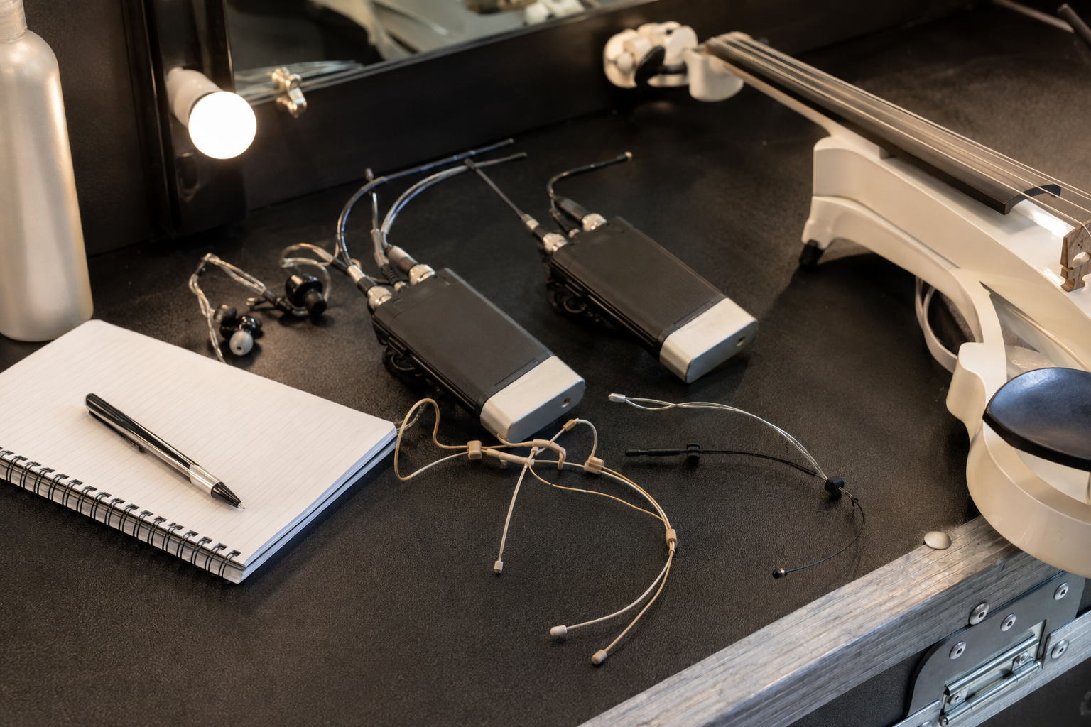 Backstage electric violin setup with dual headset microphones, wireless bodypacks, in-ear monitors, and a white violin ready for showtime