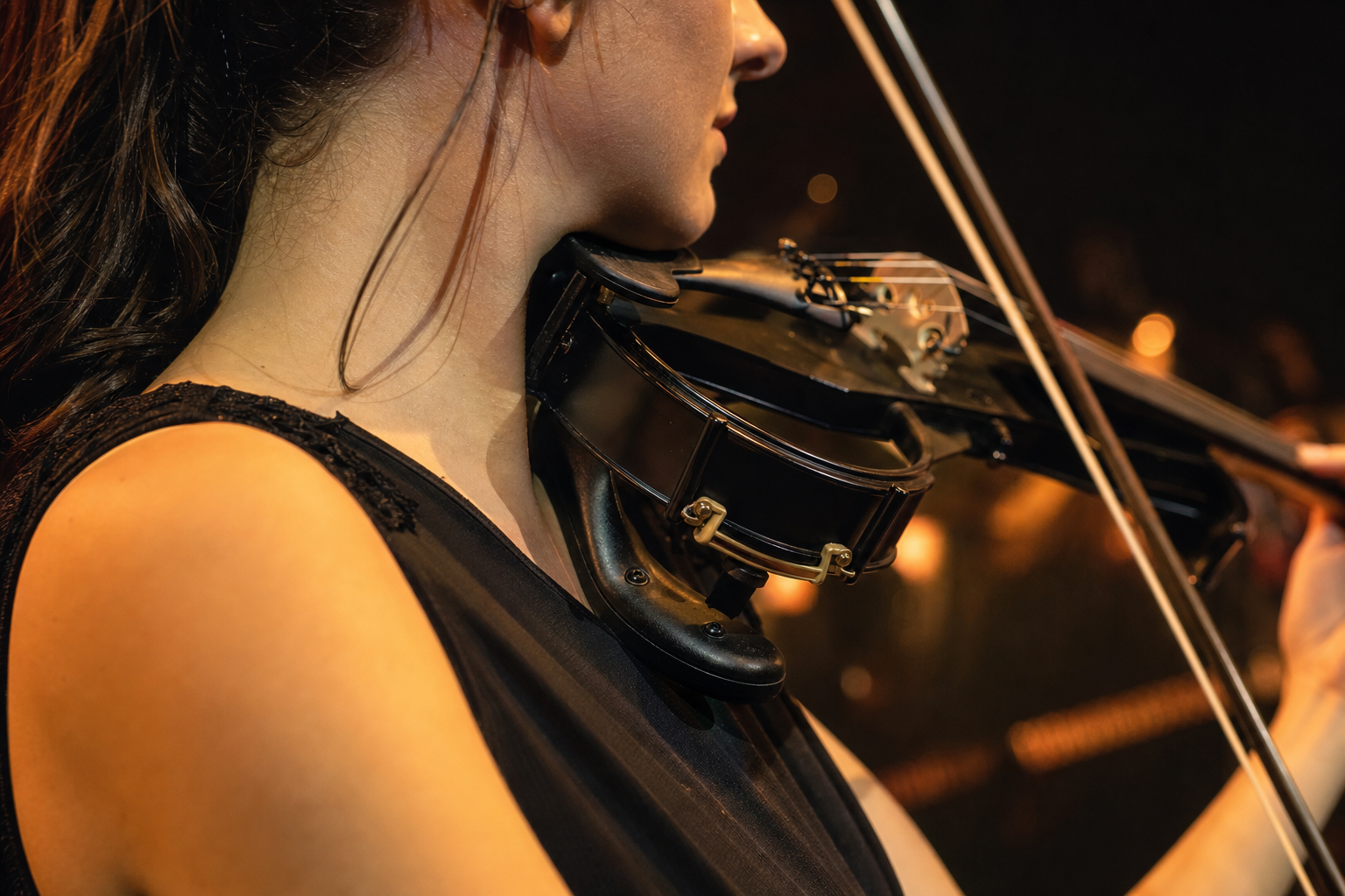 Close-up of an electric violin shoulder rest during live performance under warm stage lights