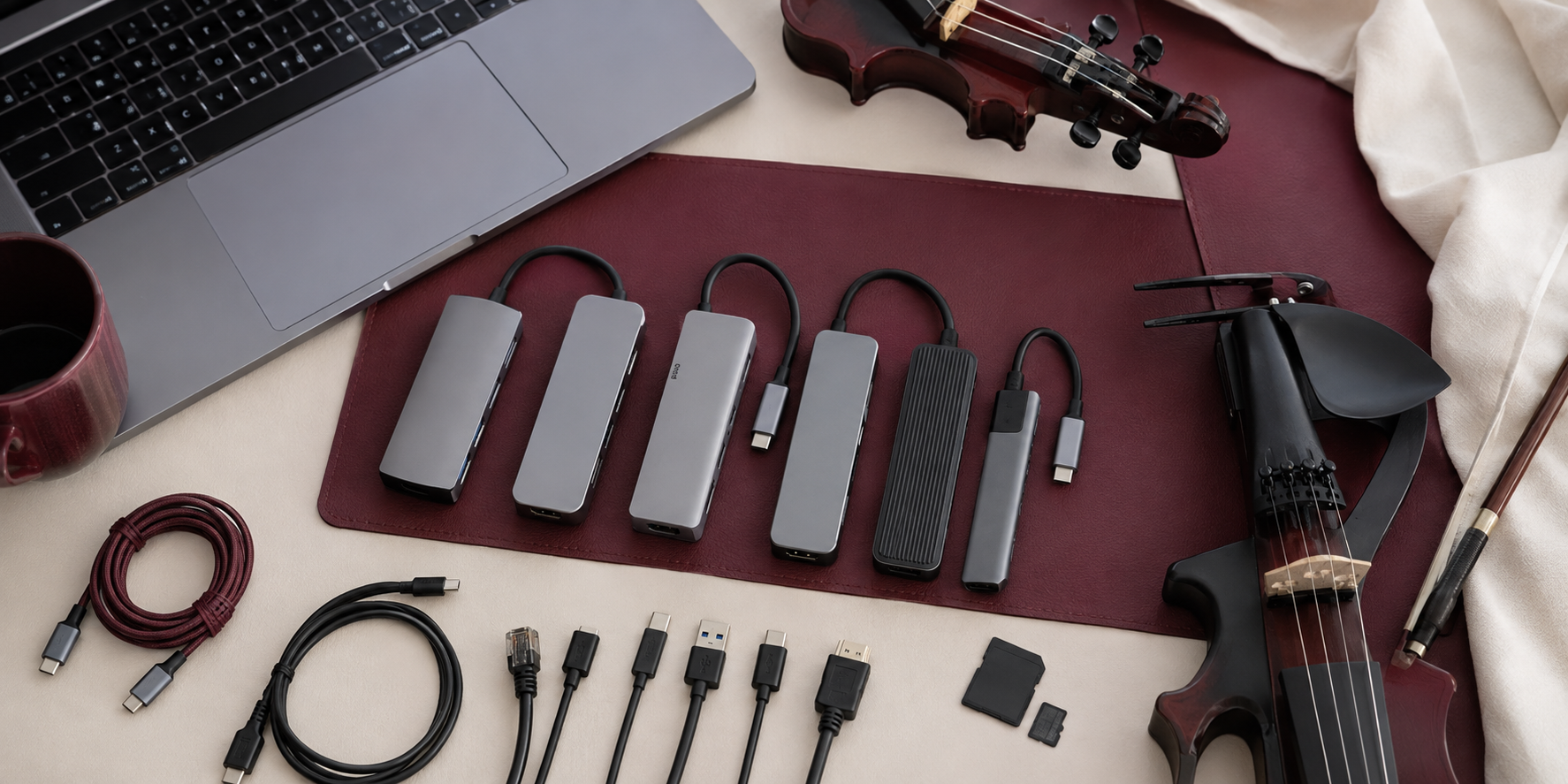 Comparison of compact USB-C hubs beside an electric violin, laptop, cards, and performance cables